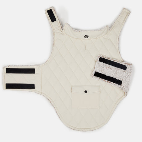 The Clearance Stratus Lite Reversible Dog Jacket features a cream quilted design, black Velcro straps, a snap pocket, and soft fleece-lined edges, shown flat on a white background.