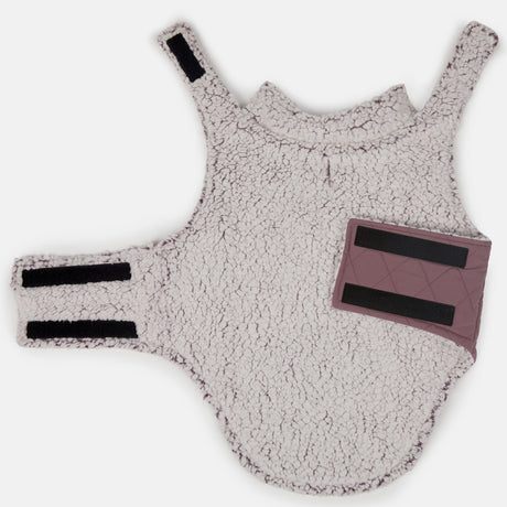 The Stratus Lite Reversible Dog Jacket by Clearance is a soft, fleece-like white harness with black Velcro straps and a mauve patch on the side, reminiscent of a sherpa-lined dog coat, shown laid flat on a white background.