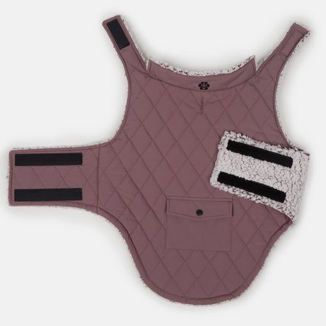 The Clearance Stratus Lite Reversible Dog Jacket is a quilted mauve, wind-resistant vest with Velcro straps, a soft white fleece lining, a small front pocket, and an adjustable sherpa-lined side piece, shown laid flat on a white background.