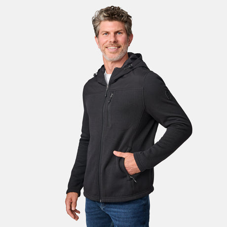 [Kolby is 6'2" wearing size M.] Men’s Free Country dark grey hooded jacket with full-zip front, zippered chest pocket, and dual side hand pockets—featuring textured fabric and a clean outdoor silhouette. Paired with beige pants for a rugged, cool-weather look.