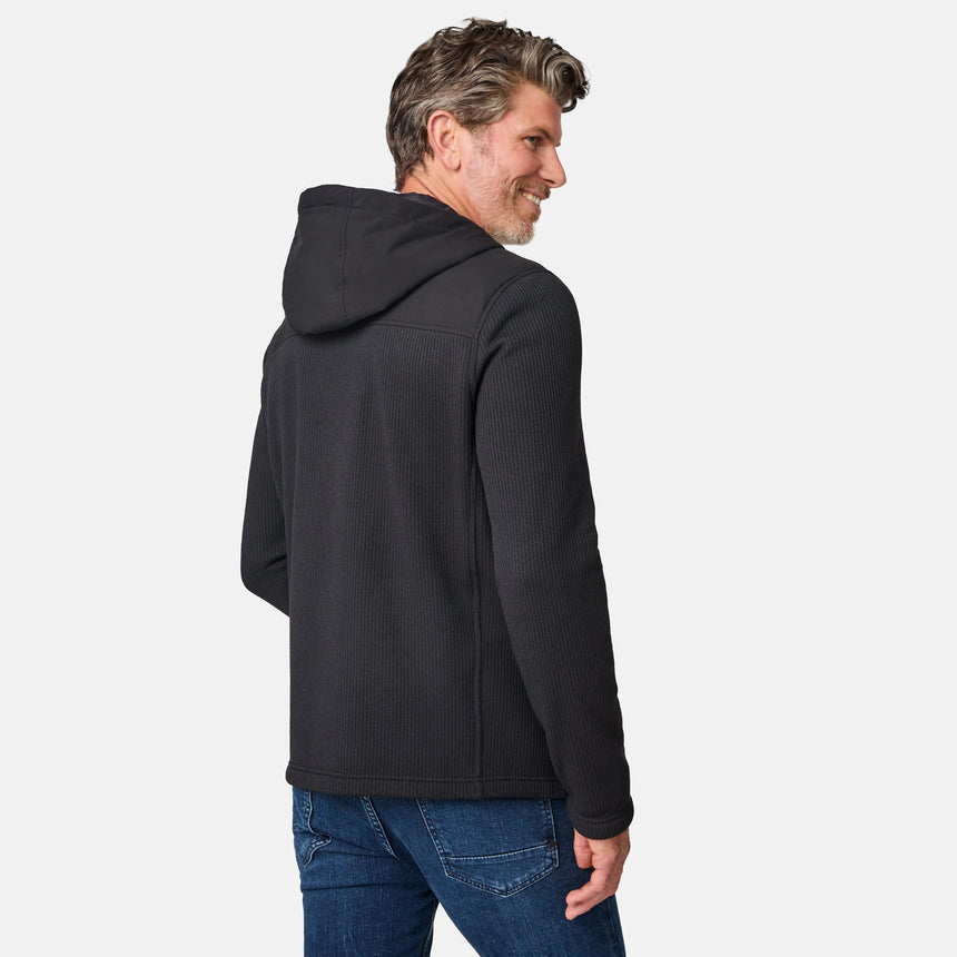 [Kolby is 6'2" wearing size M.] Men’s Free Country dark grey hooded jacket with full-zip front, zippered chest pocket, and dual side hand pockets—featuring textured fabric and a clean outdoor silhouette. Paired with beige pants for a rugged, cool-weather look.