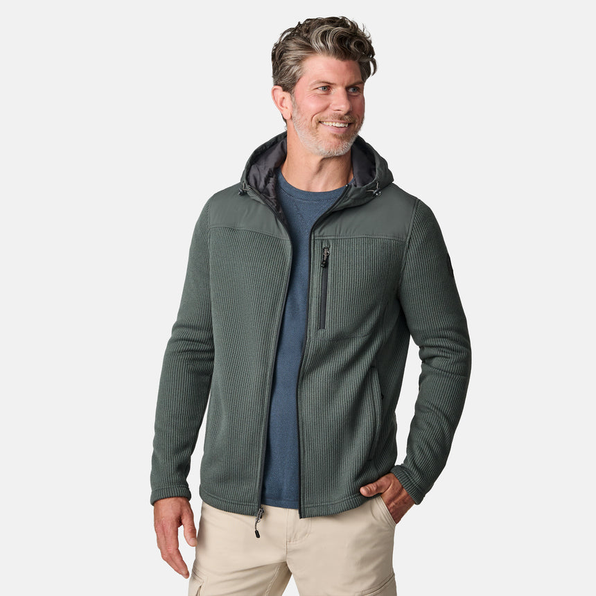 [Kolby is 6'2" wearing size M.] Men’s Free Country green hooded jacket with full-zip front, zippered chest pocket, and dual side hand pockets—featuring textured fabric and a clean outdoor silhouette. Paired with beige pants for a rugged, cool-weather look.