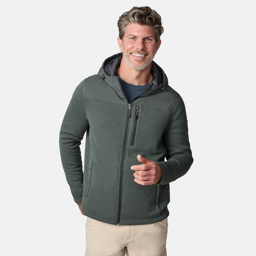 [Kolby is 6'2" wearing size M.] Men’s Free Country green hooded jacket with full-zip front, zippered chest pocket, and dual side hand pockets—featuring textured fabric and a clean outdoor silhouette. Paired with beige pants for a rugged, cool-weather look.