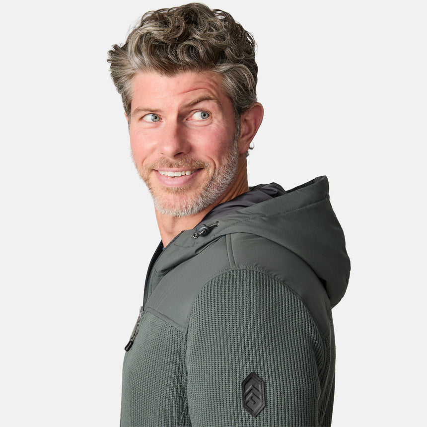 [Kolby is 6'2" wearing size M.] Men’s Free Country green hooded jacket with full-zip front, zippered chest pocket, and dual side hand pockets—featuring textured fabric and a clean outdoor silhouette. Paired with beige pants for a rugged, cool-weather look.