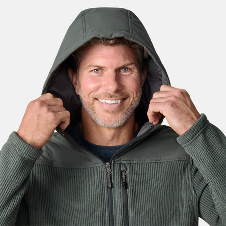 [Kolby is 6'2" wearing size M.] Men’s Free Country green hooded jacket with full-zip front, zippered chest pocket, and dual side hand pockets—featuring textured fabric and a clean outdoor silhouette. Paired with beige pants for a rugged, cool-weather look.