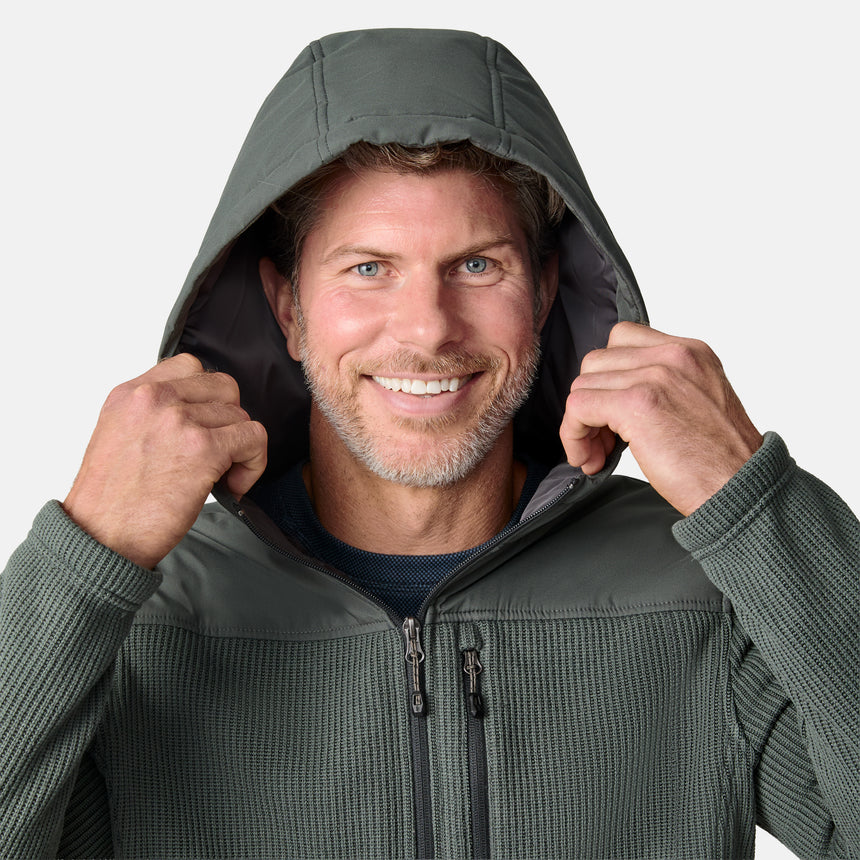 [Kolby is 6'2" wearing size M.] Men’s Free Country green hooded jacket with full-zip front, zippered chest pocket, and dual side hand pockets—featuring textured fabric and a clean outdoor silhouette. Paired with beige pants for a rugged, cool-weather look.