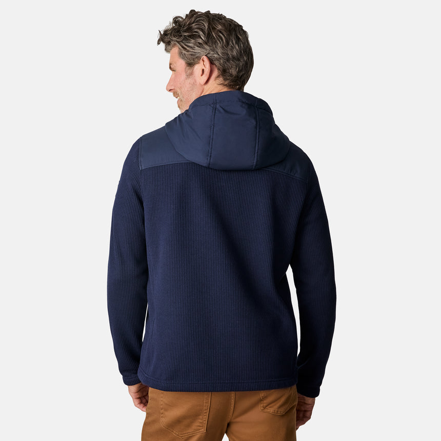 [Kolby is 6'2" wearing size M.] Men’s Free Country navy blue hooded jacket with full-zip front, zippered chest pocket, and dual side hand pockets—featuring textured fabric and a clean outdoor silhouette. Paired with beige pants for a rugged, cool-weather look.