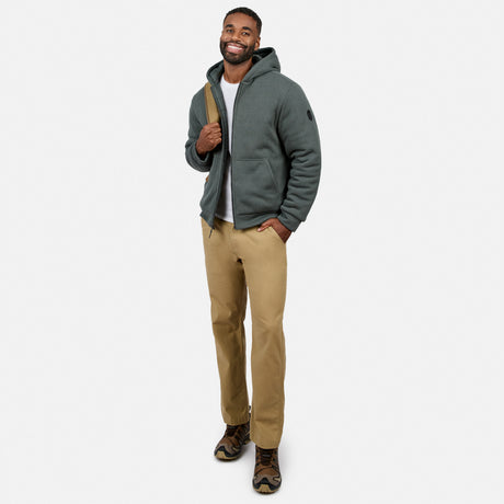 Smiling man wearing a teal quilted reversible jacket zipped up over a white tee and khaki pants.