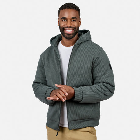 Man wearing dark green ribbed fleece reversible jacket with hood over a white T-shirt, arms crossed.