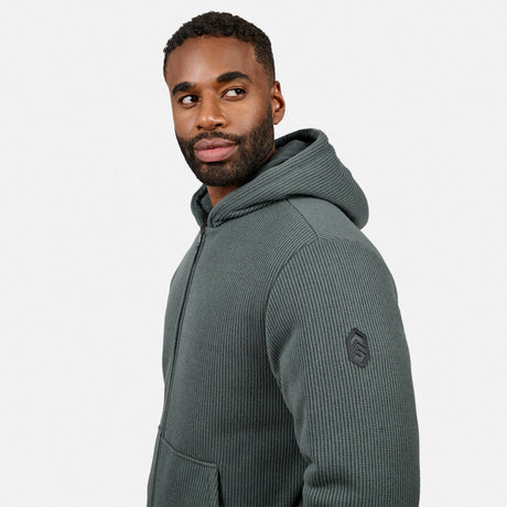 Side profile of a man in the same jacket showing textured knit fabric, zip and sleeve patch detail.