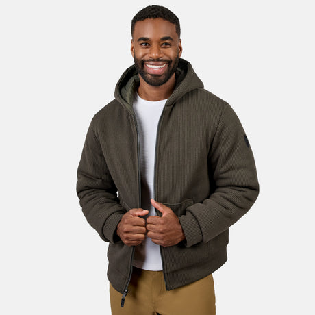 Man wearing Men's Chayote Cable Fleece Reversible Jacket in olive green quilted hooded jacket with zipper and hands near the zipper