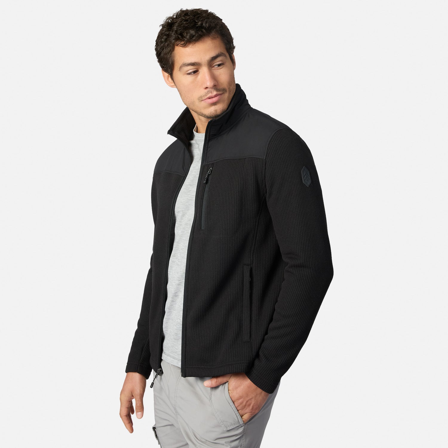 [Model is wearing size M.] A man wearing a black and dark gray quarter-zip fleece jacket over a light gray t-shirt and gray pants, photographed against a solid light gray background.