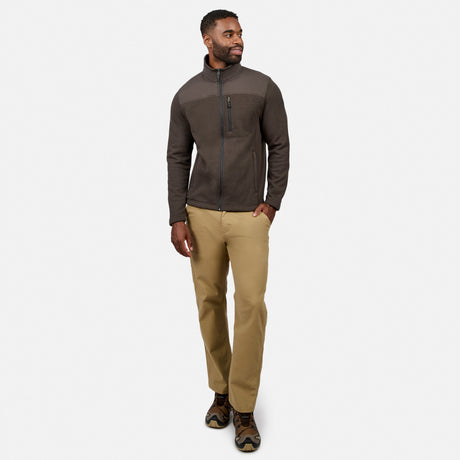 [Model is wearing size M.] A man wearing a dark brown and charcoal gray zip-up fleece jacket, tan pants, and brown hiking boots, standing against a light gray studio background.