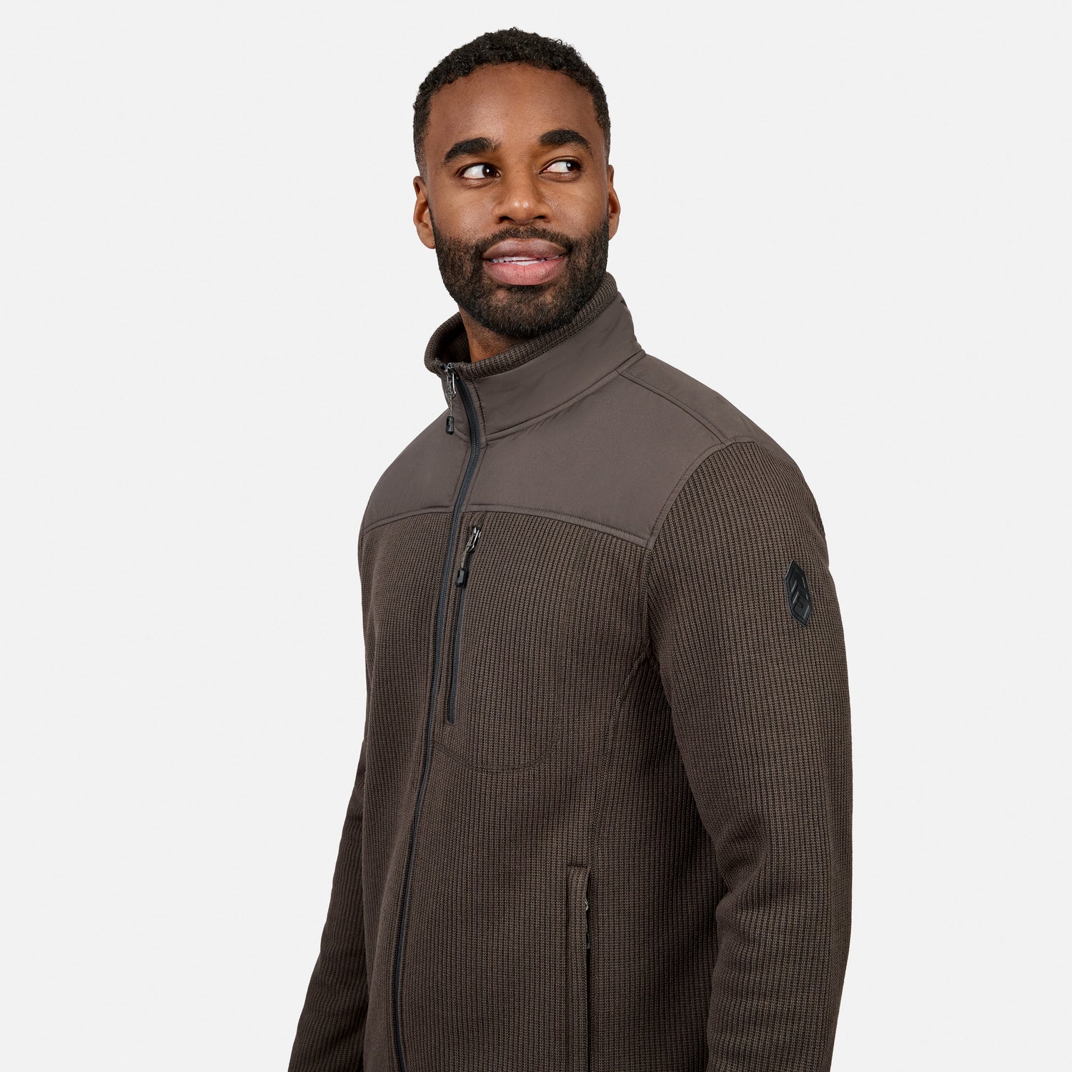 [Model is wearing size M.] A man wearing a dark brown ribbed fleece jacket with a stand-up collar and zippered chest pocket, photographed against a clean light gray studio background.