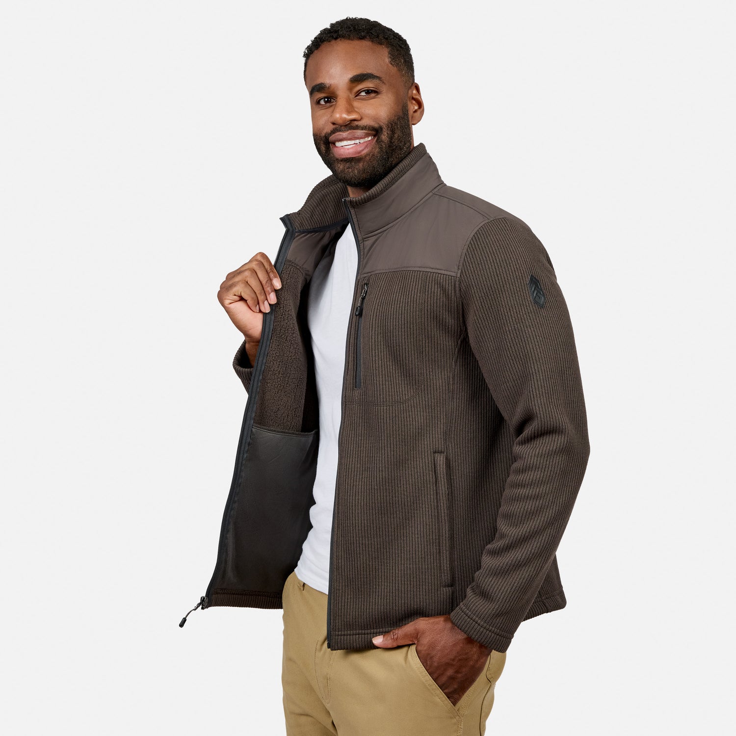 [Model is wearing size M.] A man wearing a dark brown and gray ribbed zip-up fleece jacket over a white t-shirt and khaki pants, standing against a light gray studio background.