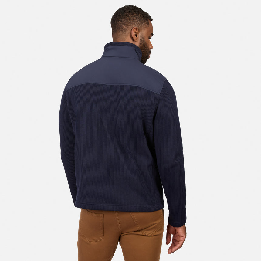 [Model is wearing size M.] A man wearing a navy blue quarter-zip fleece pullover with a contrasting dark gray shoulder yoke, shown from a rear three-quarter view against a light gray background.
