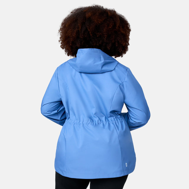 A woman with curly hair is shown from the back wearing the Free Country Women's Plus Size X2O Anorak Rain Jacket in light blue. This water-resistant jacket features long sleeves and an elastic waistband. The background is plain white.