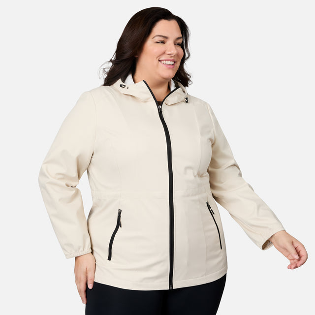 A woman wearing the Free Country Women's Plus Size X2O Anorak Rain Jacket, featuring black zippers, smiles and poses against a plain white background.