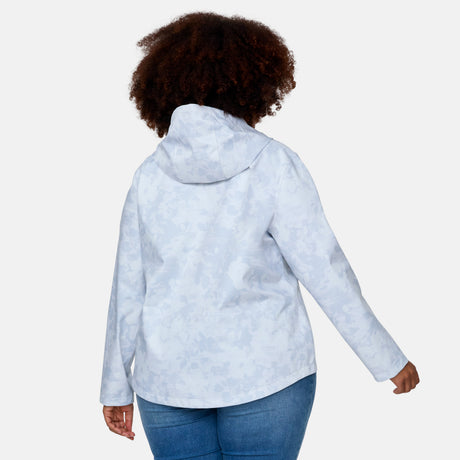 A person with curly hair is seen from the back, wearing the Free Country Women's Plus Size X2O Packable Rain Jacket in light blue with a subtle floral pattern and blue jeans, standing against a plain light background.
