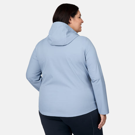 A person is seen from behind wearing the Free Country Women's Plus Size X2O Packable Rain Jacket in light blue with dark pants, standing against a plain white background.