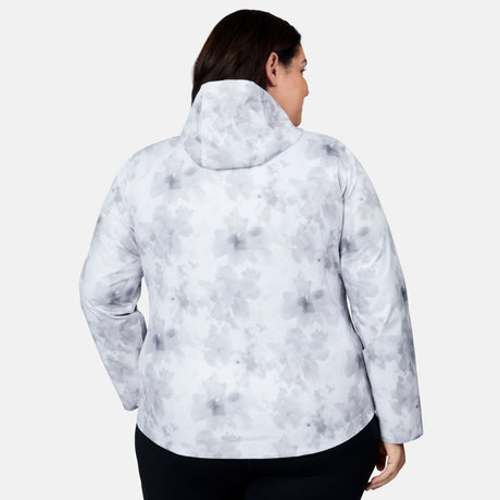A woman is shown from the back wearing the Free Country Women's Plus Size X2O Packable Rain Jacket, featuring a light gray and white floral pattern with a hood, against a plain white background.
