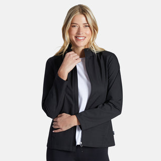 A woman with long blonde hair smiles while wearing the Free Country Women's X2O Packable Rain Jacket in black over a white shirt, standing against a plain light gray background.