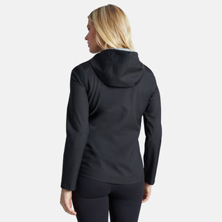 A woman with blonde hair is shown from the back wearing the Free Country Women's X2O Packable Rain Jacket in black and black leggings, standing against a plain light gray background.
