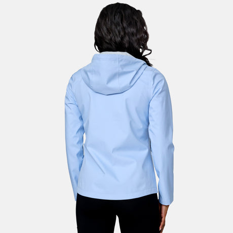 A person with long, wavy hair is shown from the back wearing the Free Country Women's X2O Packable Rain Jacket in light blue and black pants against a plain white background.