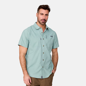 [Justin is 6'1" wearing a size Medium.] Man wearing the Free Country Men's Acadia Short Sleeve Shirt in Basil, size M, featuring a short sleeves, mesh underarm panels for breathability, and a zipper chest pocket made from lightweight polyester fabric, styled with khaki shorts #color_ basil