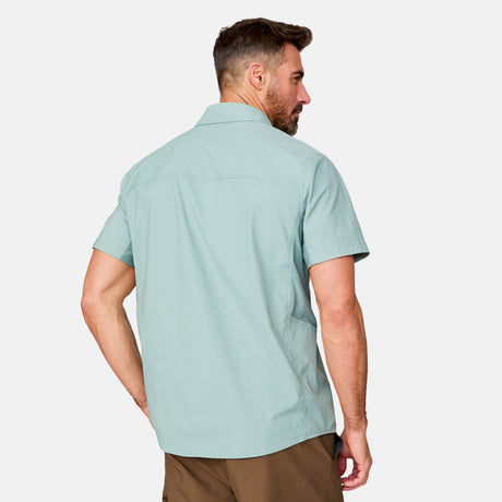 [Justin is 6'1" wearing a size Medium.] Man wearing the Free Country Men's Acadia Short Sleeve Shirt in Basil, size M, featuring a short sleeves, mesh underarm panels for breathability, and a zipper chest pocket made from lightweight polyester fabric, styled with khaki shorts #color_ basil