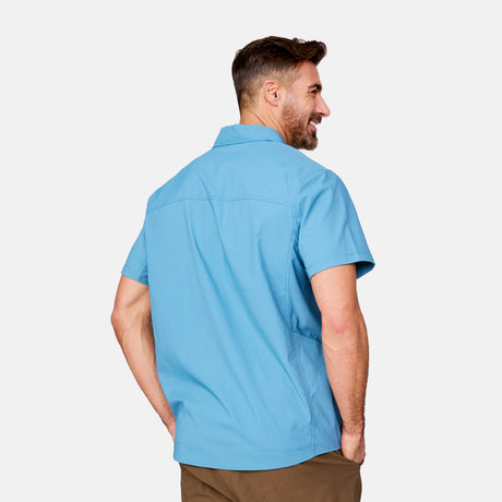 [Justin is 6'1" wearing a size Medium.] Man wearing the Free Country Men's Acadia Short Sleeve Shirt in BLUESTONE, size M, featuring a short sleeves, mesh underarm panels for breathability, and a zipper chest pocket made from lightweight polyester fabric, styled with khaki shorts #color_ bluestone