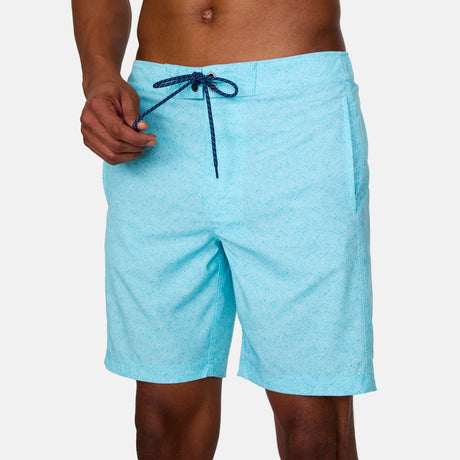 [Anderson is 6'2" wearing a size Medium.] Man wearing Free Country Men's Textured Surf Swim Short in Aqua, size M, made from moisture wicking stretch performance fabric featuring  a half back elastic waistband and fly front drawstring front closure #color_aqua