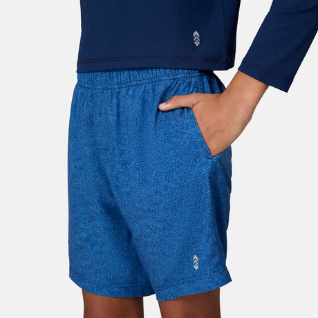 [Emporer is wearing size 10/12 Medium] child wearing blue textured swim shorts with a brand logo on a white background.
