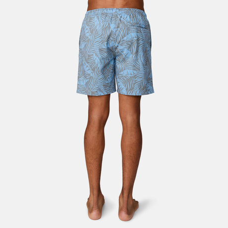 [Josiah is 6'3" wearing a size Medium.] Man wearing Free Country Men's Palm Heaven Swim Short in Bluestone Plam Heaven, size M, made from lightweight stretch recycled polyester performance fabric featuring a full elastic waistband with a drawcord, UPF and quick dry technology, and side seam pockets #color_bluestone-palm-heaven