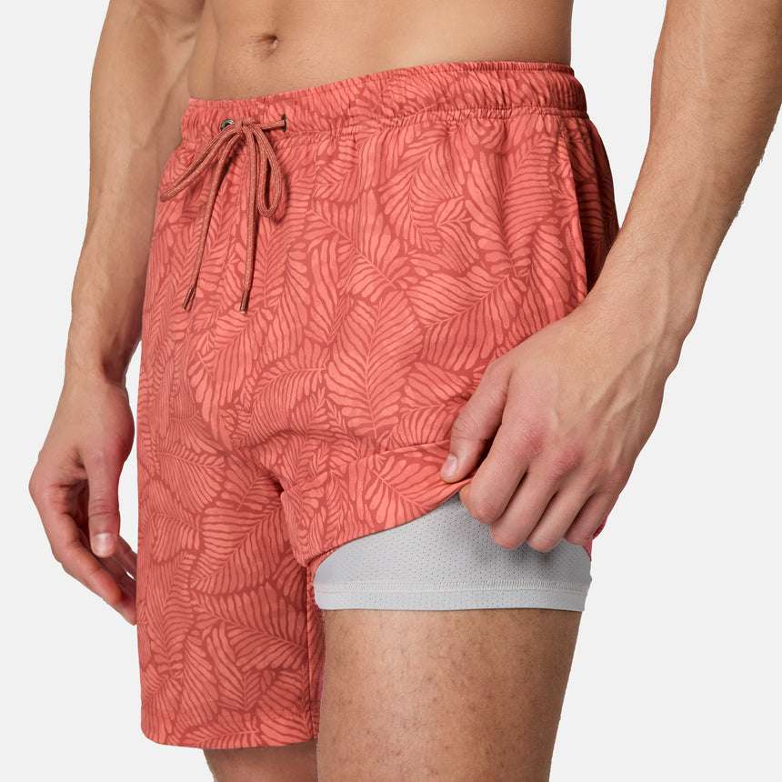 [Model is wearing size M] Person wearing red patterned swim shorts on a white background