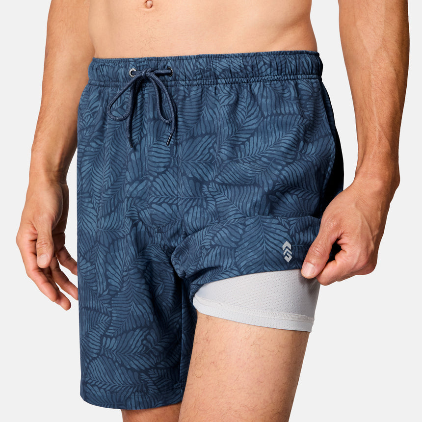 [Model is wearing size M] Blue patterned swim shorts worn by a person on a white background