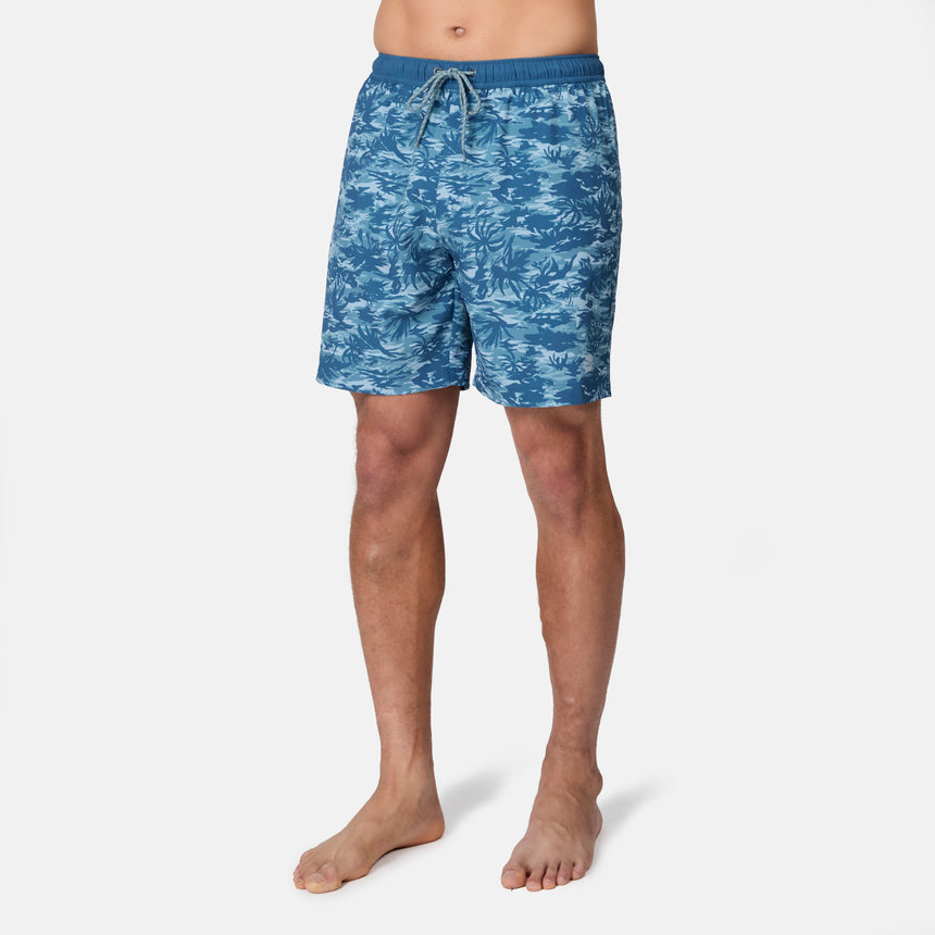 A person stands barefoot in Free Country Men's Surf Camo Swim Short, which features an elastic waistband and drawstring. These UPF 50+ trunks offer style and sun protection, shown against a plain white background.