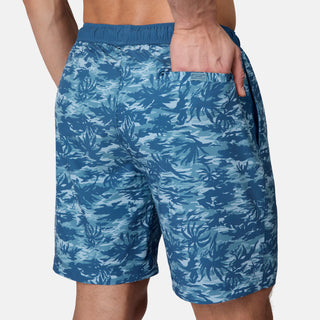 A person wears the Free Country Men's Surf Camo Swim Short with an elastic waistband and side pocket, standing against a plain light background. This swim short offers comfort and UPF 50+ protection.
