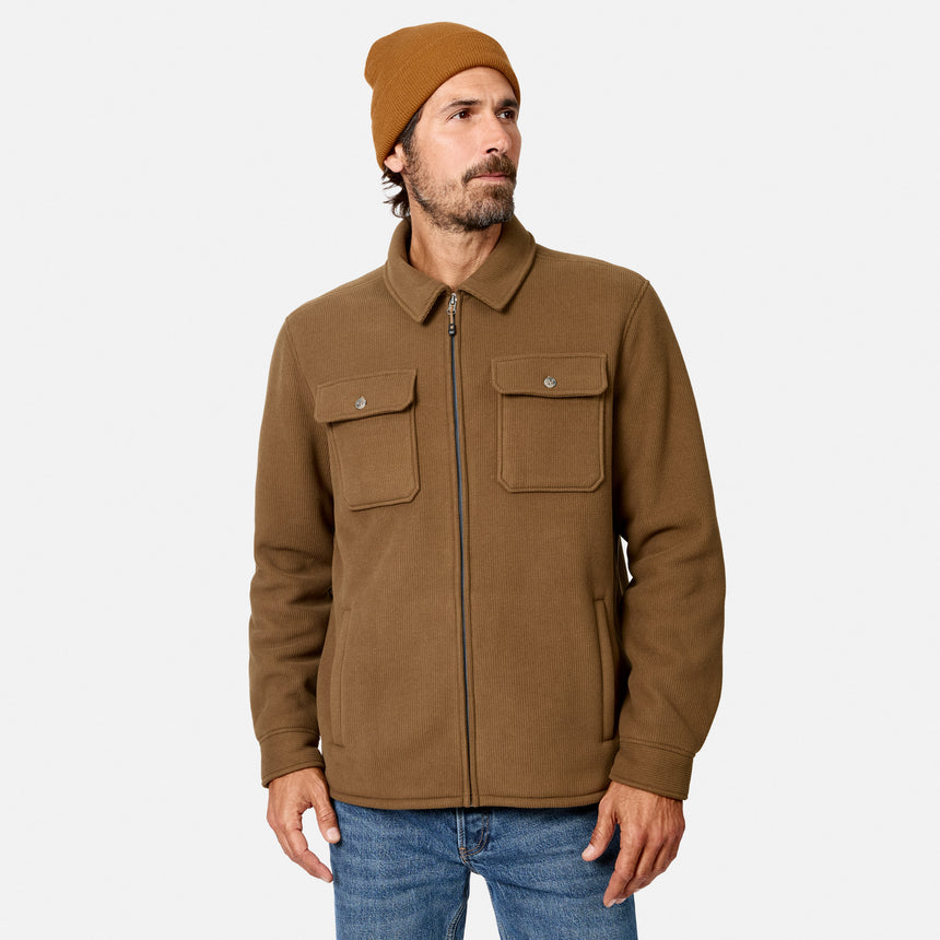 [Model is wearing size M.] A man wearing a brown zip-up jacket with two chest pockets, a matching brown beanie, and blue jeans, photographed against a light gray studio background.