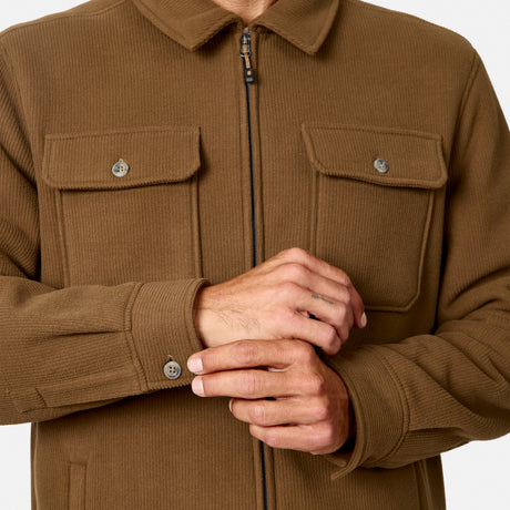 [Model is wearing size M.] A close-up of a person wearing a brown corduroy zip-front jacket with two chest flap pockets and buttoned cuffs, shown against a plain light background.