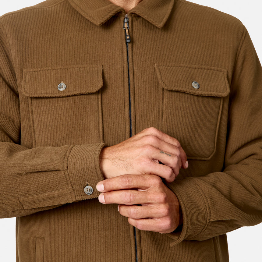 [Model is wearing size M.] A close-up of a person wearing a brown corduroy zip-front jacket with two chest flap pockets and buttoned cuffs, shown against a plain light background.