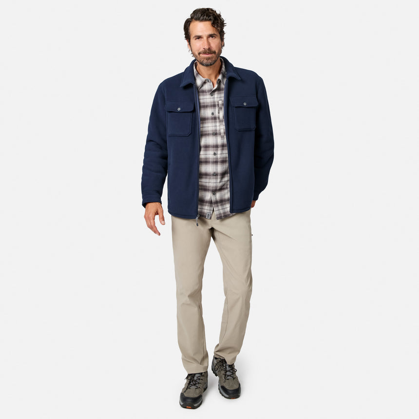 [Model is wearing size M.] A man modeling a navy blue utility jacket over a gray and white plaid flannel shirt, paired with beige hiking pants and dark hiking boots, against a light gray studio background.
