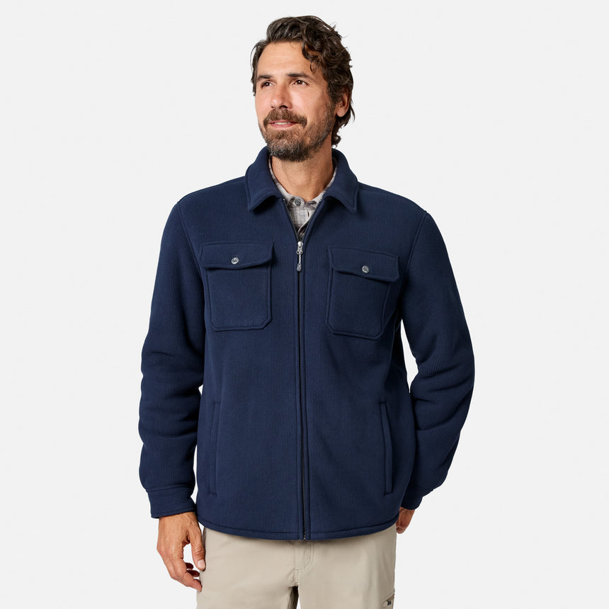 [Model is wearing size M.] A man wearing a navy blue zip-up fleece jacket over a light gray collared shirt and khaki pants, standing against a light gray studio background.