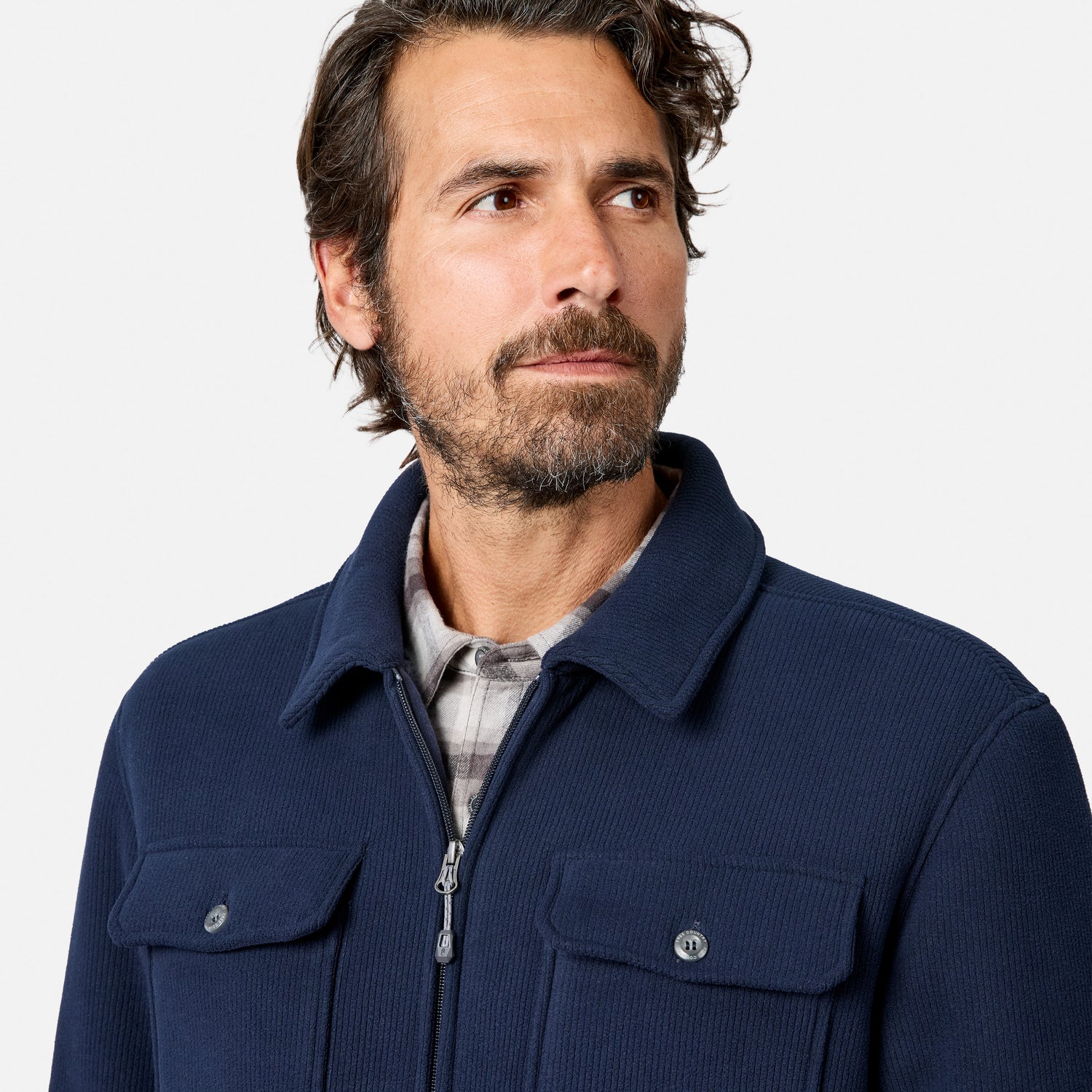 [Model is wearing size M.] A man wearing a navy blue corduroy zip-up jacket over a plaid shirt, photographed against a clean light gray studio background.