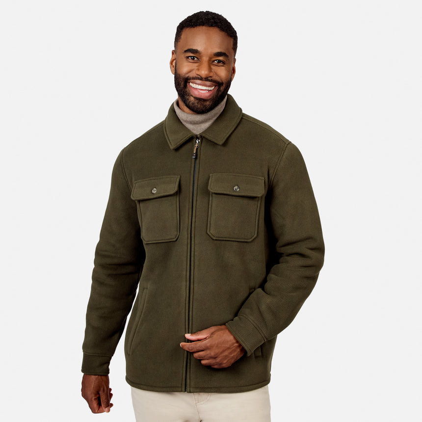 [Model is wearing size M.] A smiling man wearing an olive green zip-up jacket over a beige turtleneck sweater and cream pants, photographed against a clean light gray studio background.