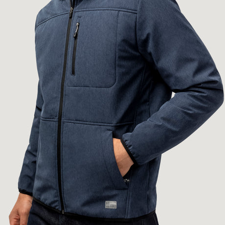 A person wears the Men's Melange Stretch Full Zip Hoodie by Clearance in blue, featuring wind and water resistance, a zippered chest pocket, visible stitching, and stands with one hand in the pocket against a plain light background.