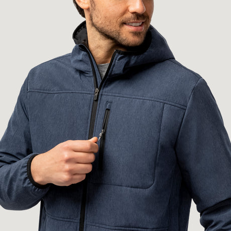 A man in the Clearance Men's Melange Stretch Full Zip Hoodie, which is wind and water resistant, smiles while zipping a small chest pocket against a plain light gray background.