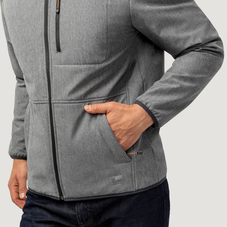 A person wears the Men's Melange Stretch Full Zip Hoodie by Clearance in light gray, wind and water resistant, with their right hand in a front pocket, paired with dark blue jeans against a plain light background.