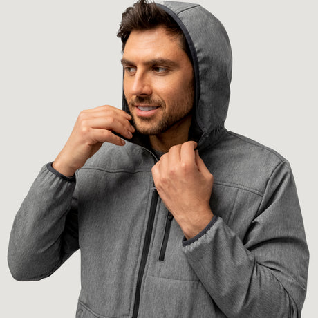 A man zips up the Men's Melange Stretch Full Zip Hoodie by Clearance, featuring wind and water resistance, while looking to the side against a plain light background.