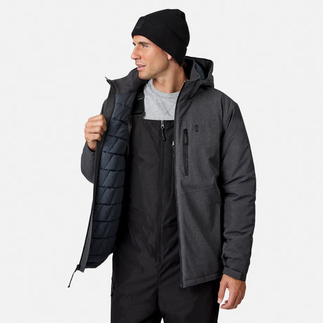 [Model is wearing size M.] A man wearing a dark gray hooded technical jacket over a black ski suit and a black beanie, holding the jacket open to show the dark quilted lining, set against a plain light gray background.